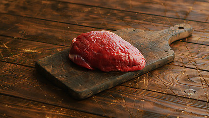 Image showing Big fresh piece of meat laid on wooden cutting board