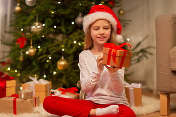 Image showing smiling girl in santa hat with christmas gift