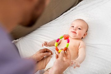 Image showing close up of father giving rattle to baby girl