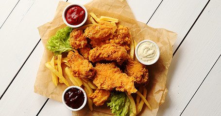 Image showing Sauces and lettuce near French fries and chicken wings