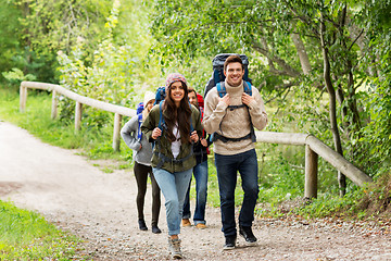 Image showing happy friends or travelers hiking with backpacks