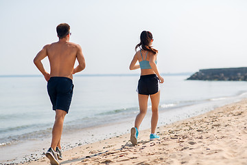 Image showing couple in sports clothes running along on beach