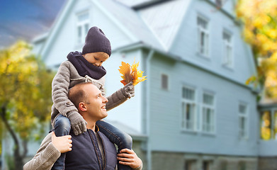 Image showing father and son with autumn maple leaves over house