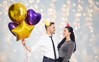 Image showing happy couple in party hats with balloons