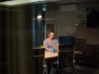 Image showing man working on laptop in dark office