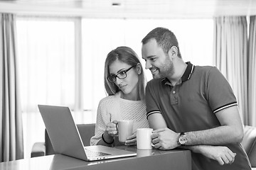 Image showing couple drinking coffee and using laptop at home