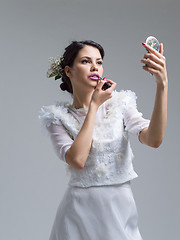 Image showing bride paints lips with lipstick