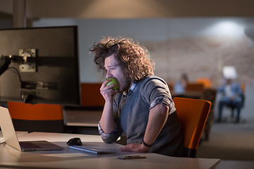 Image showing man eating apple in his office