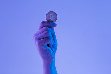 Image showing Male hand with golden bitcoin on blue background