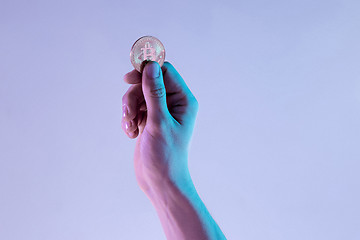 Image showing Male hand with golden bitcoin on blue background