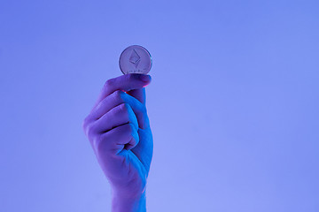 Image showing Male hand with golden Ethereum on blue background