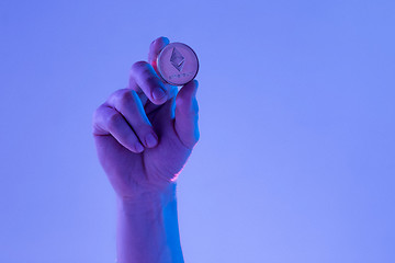 Image showing Male hand with golden Ethereum on blue background