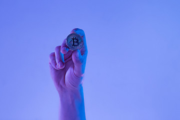 Image showing Male hand with golden bitcoin on blue background