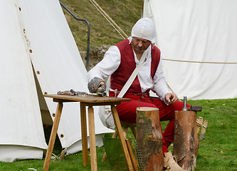 Image showing Man dressed in Medieval clothes making metal armour 