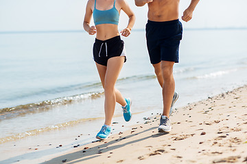 Image showing couple in sports clothes running along on beach