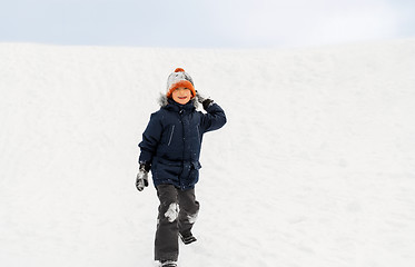 Image showing happy boy playing and throwing snowball in winter