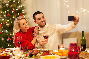 Image showing happy couple taking selfie at christmas dinner