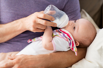 Image showing close up of father feeding baby from bottle