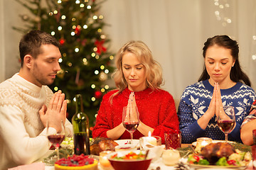 Image showing friends praying before christmas dinner at home 