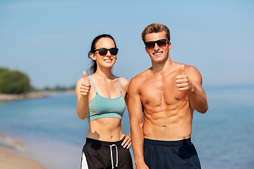 Image showing couple of athletes showing thumbs up on beach