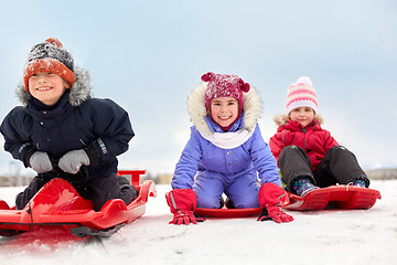 Image showing happy little kids sliding down on sleds in winter