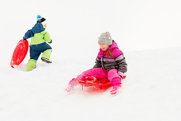 Image showing happy kids sliding on sleds down hill in winter