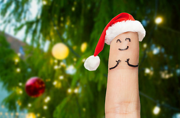 Image showing one finger in santa hat over christmas tree