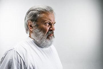 Image showing Senior man with disgusted expression repulsing something on white