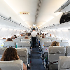 Image showing Interior of commercial airplane with passengers on their seats during flight.