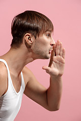 Image showing Isolated on pink young casual man shouting at studio