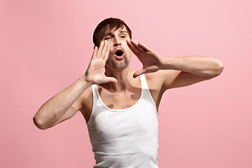 Image showing Isolated on pink young casual man shouting at studio