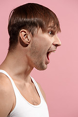 Image showing The young emotional angry man screaming on pink studio background