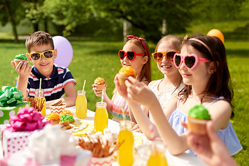 Image showing kids eating cupcakes on birthday party in summer