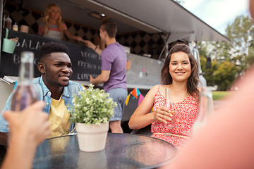 Image showing friends with drinks sitting at table at food truck