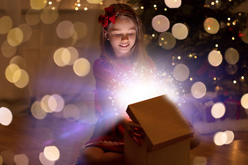 Image showing smiling girl opening christmas gift at night