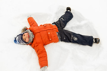 Image showing happy little boy making snow angels in winter
