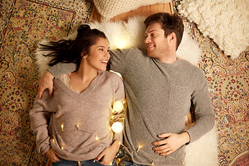 Image showing happy couple with garland lying on floor at home