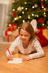 Image showing smiling girl writing christmas wish list at home