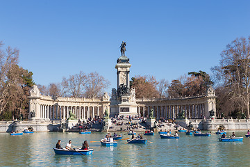 Image showing Tourists rowing traditional blue boats on lake in Retiro city park on a nice sunny winter day in Madrid, Spain.