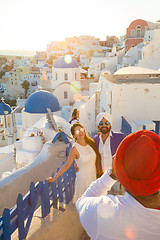 Image showing Indian tourists taking photos of colorful Oia village on Santorini island, Greece.