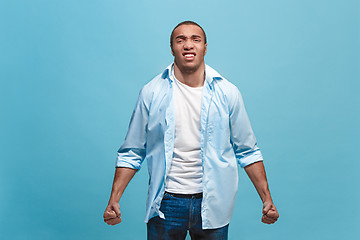 Image showing The young emotional angry man screaming on blue studio background