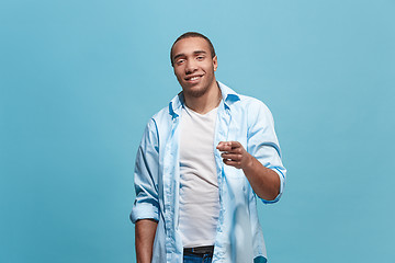 Image showing The happy business man point you and want you, half length closeup portrait on blue background.