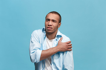 Image showing Young man overwhelmed with a pain in the shoulder .