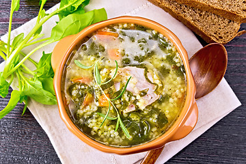 Image showing Soup with couscous and spinach in clay bowl on board top