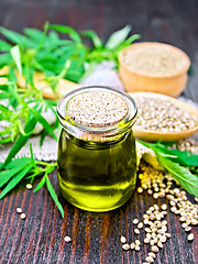 Image showing Oil hemp in jar with flour and grain on dark board