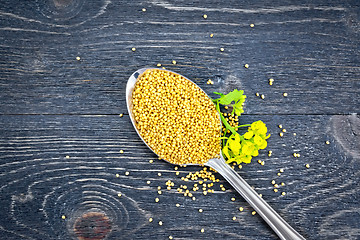 Image showing Mustard seeds in metal spoon with flower on board top