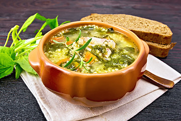 Image showing Soup with couscous and spinach in clay bowl on wooden table