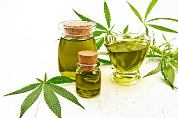 Image showing Oil hemp in gravy boat and two jars on light board