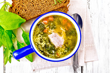 Image showing Soup with couscous and spinach in blue bowl on board top