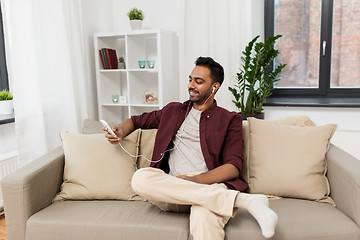 Image showing man in earphones listening to music on smartphone